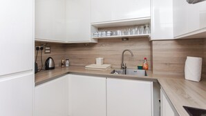 A modern kitchen with white cabinets, a wooden countertop, a sink, and various kitchen appliances. - Cosy and Spacious 3 BD flat on Bermondsey St (London)