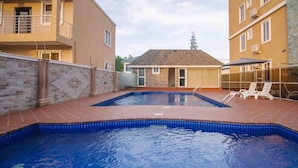 Une piscine rectangulaire dont les bords sont recouverts de carreaux, entourée d’une terrasse en briques.