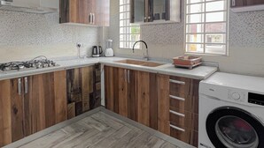Une cuisine moderne avec des meubles en bois, une cuisinière encastrée, un évier et un lave-linge.