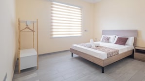 Une chambre à coucher avec un lit, une table de chevet et un portant à vêtements.