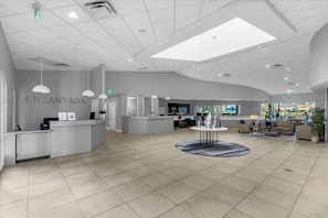 A spacious lobby with a reception desk, seating area, and a large window providing natural light.