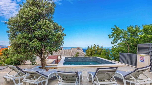 Un espace piscine aménagé sur le toit, avec des chaises longues et une vue sur la ville.