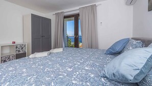 Une chambre à coucher comprenant un lit, une armoire, une table de chevet et un balcon avec vue.