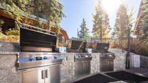 A stone-built outdoor kitchen with three grills, a gas safety sign, and a metal grate. - MARRIOTT Resort AUG 26,27 -130 USD-Hot tub -GYM -Kitchen (South Lake Tahoe)