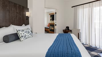 A hotel room with a large bed, a fireplace, a desk, and a chair.