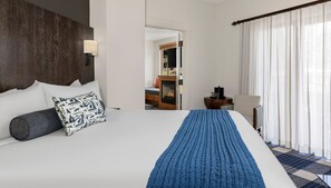 Una habitación de hotel con una cama grande, una chimenea, un escritorio y una silla.