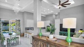 A spacious living area with a pool view, a wooden cabinet with decorative carvings, and a ceiling fan. - Luxurious SW Florida Pool Home (Cape Coral)