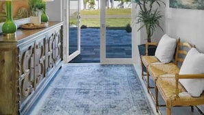 A spacious hallway with a chandelier, a large painting, and a view of the outdoors. - Luxurious SW Florida Pool Home (Cape Coral)