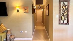Un pasillo con televisión de pantalla plana, lámparas de pared, un reloj y cuadros enmarcados.