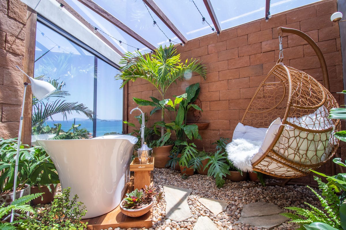 A sunlit patio with a hanging chair, potted plants, and a large white planter.
