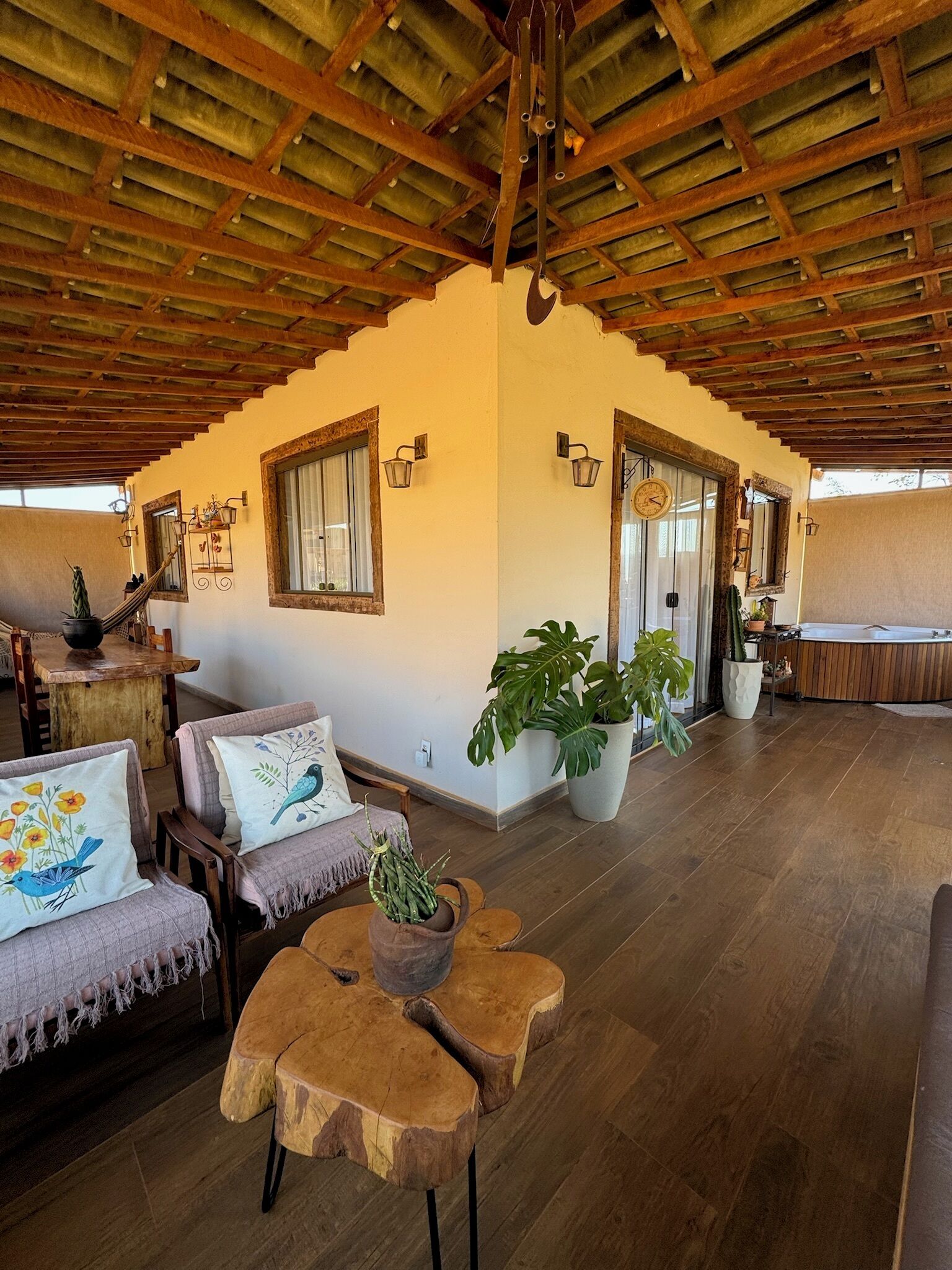 Une pièce spacieuse avec un plafond en bois, de grandes fenêtres et un coin salon confortable avec un canapé et des fauteuils.