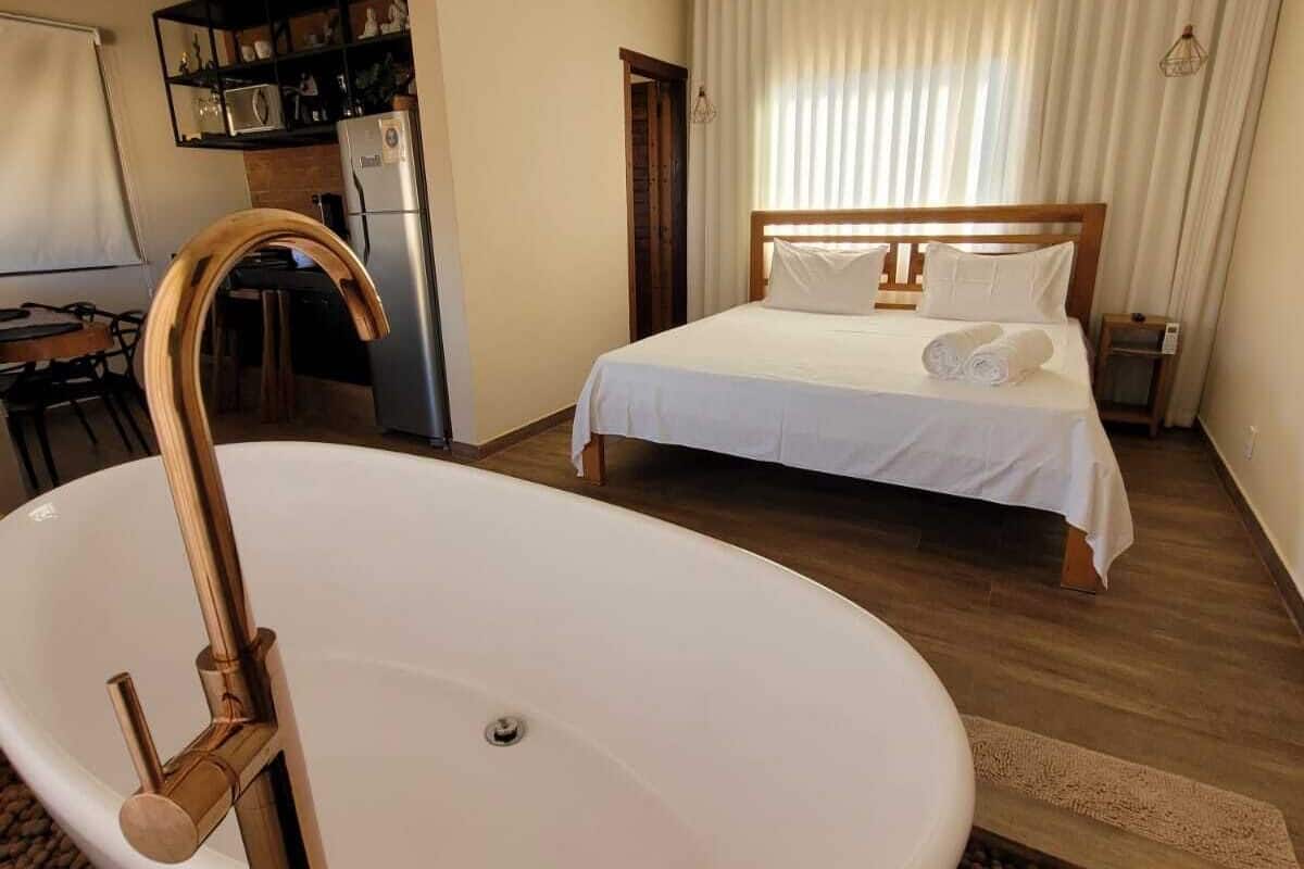 Une chambre d’hôtel dotée d’une grande baignoire sur pieds, d’un lit avec du linge de maison blanc et d’un coin cuisine.