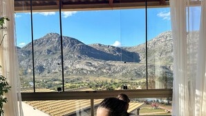 A person in a bathtub with a mountain view through large windows. - Euetu na Lapinha da Serra (Santana do Riacho)