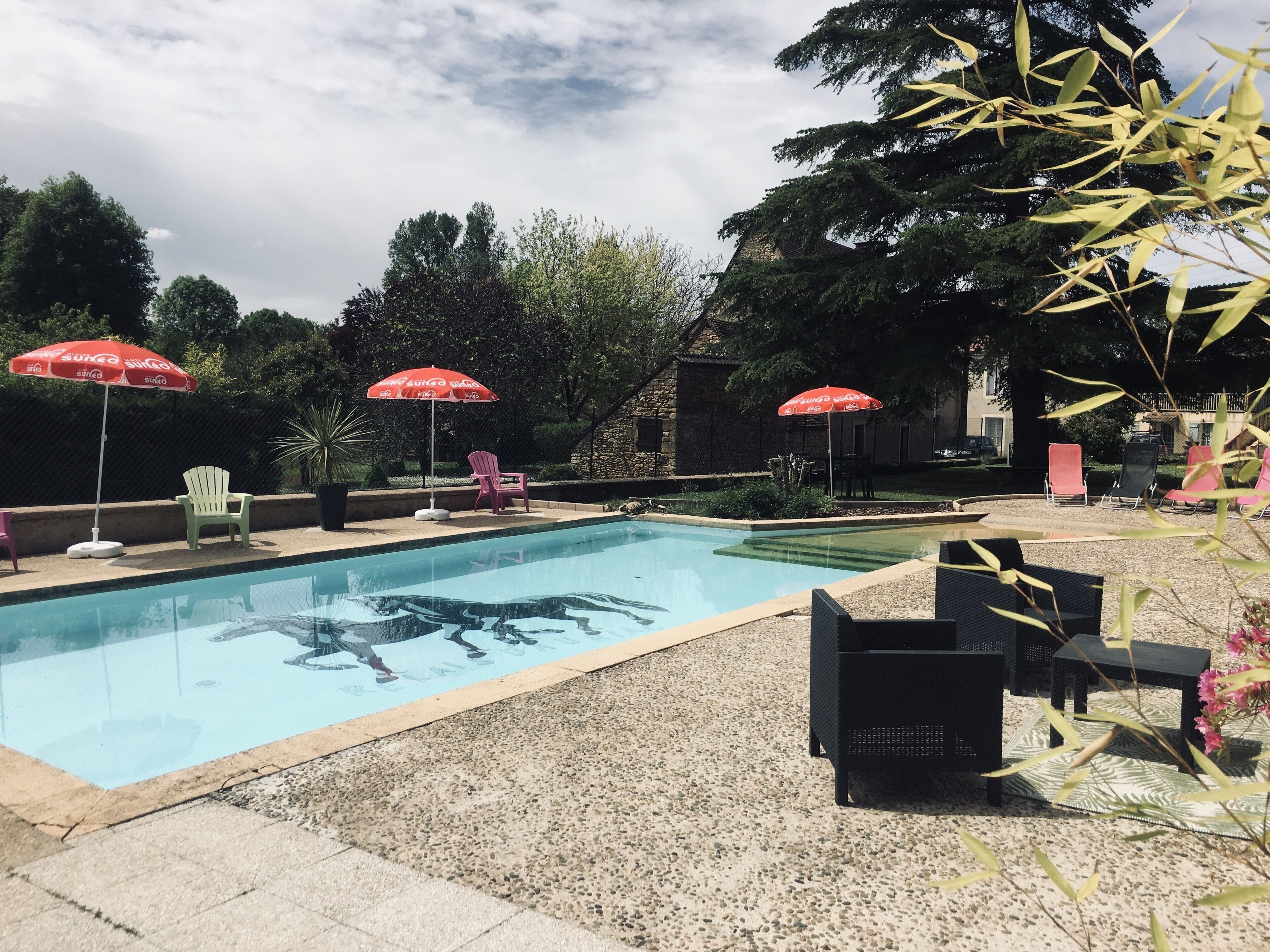 Una piscina con sillones y sombrillas.
