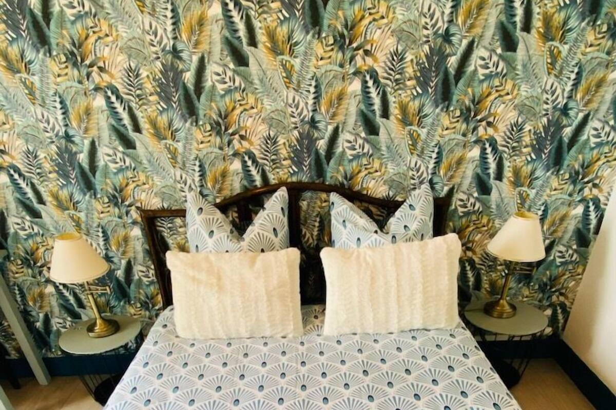 Un lit avec une couvre-lit à motifs et des oreillers, flanqué de deux tables de chevet sur lesquelles sont posées des lampes.