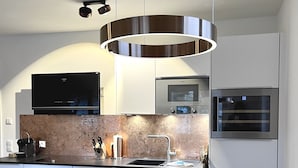 A modern kitchen with a built-in oven, microwave, and a large stainless steel range hood. - Cabinet Riedersteinblick in Rottach-Egern am Tegernsee  (Rottach-Egern)