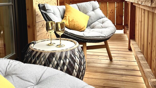 A wooden deck with a cushioned chair and a round table, both with cushions. - Cabinet Riedersteinblick in Rottach-Egern am Tegernsee  (Rottach-Egern)