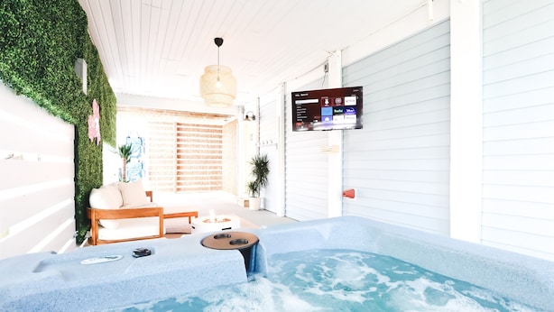 Et spa-område med jacuzzi, træbænke og et tv på væggen.