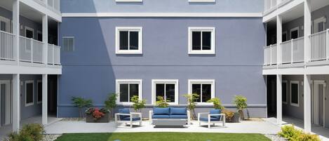 A multi-story building with balconies, a courtyard with seating, and a well-maintained lawn.