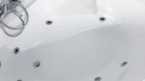 A white bathtub with multiple drain holes and a metal ring. - Balneo bath accommodation (Varzy)