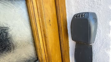 En dør med et matteret glasfelt og et sort intercomsystem.