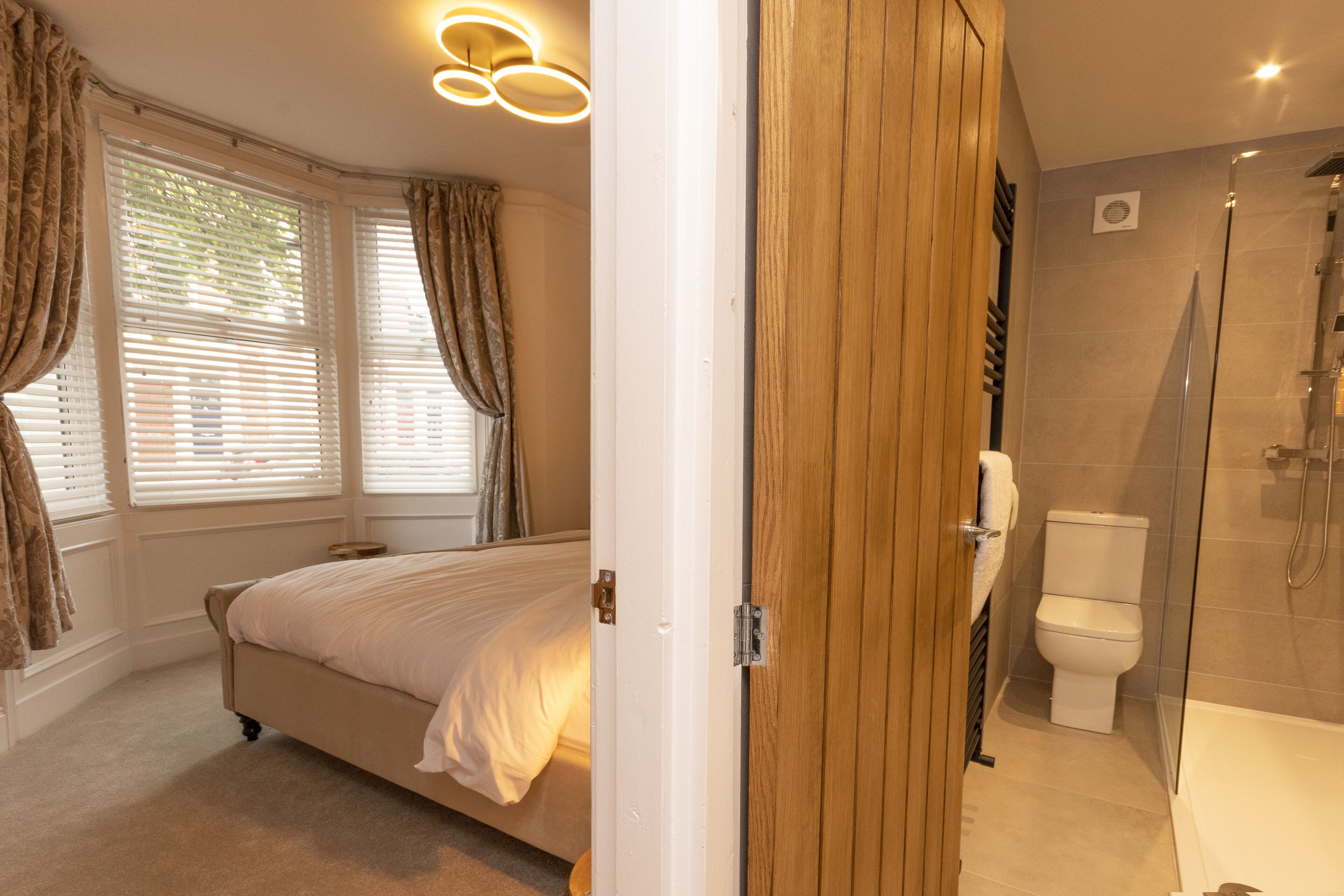 A bedroom with a bed, a bathroom with a toilet and shower, and a wooden door.