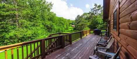 Une terrasse en bois, agrémentée de chaises, qui offre une vue imprenable sur une forêt verdoyante.