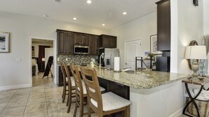 A kitchen with dark wooden cabinets, a granite countertop, and a built-in island with bar stools.