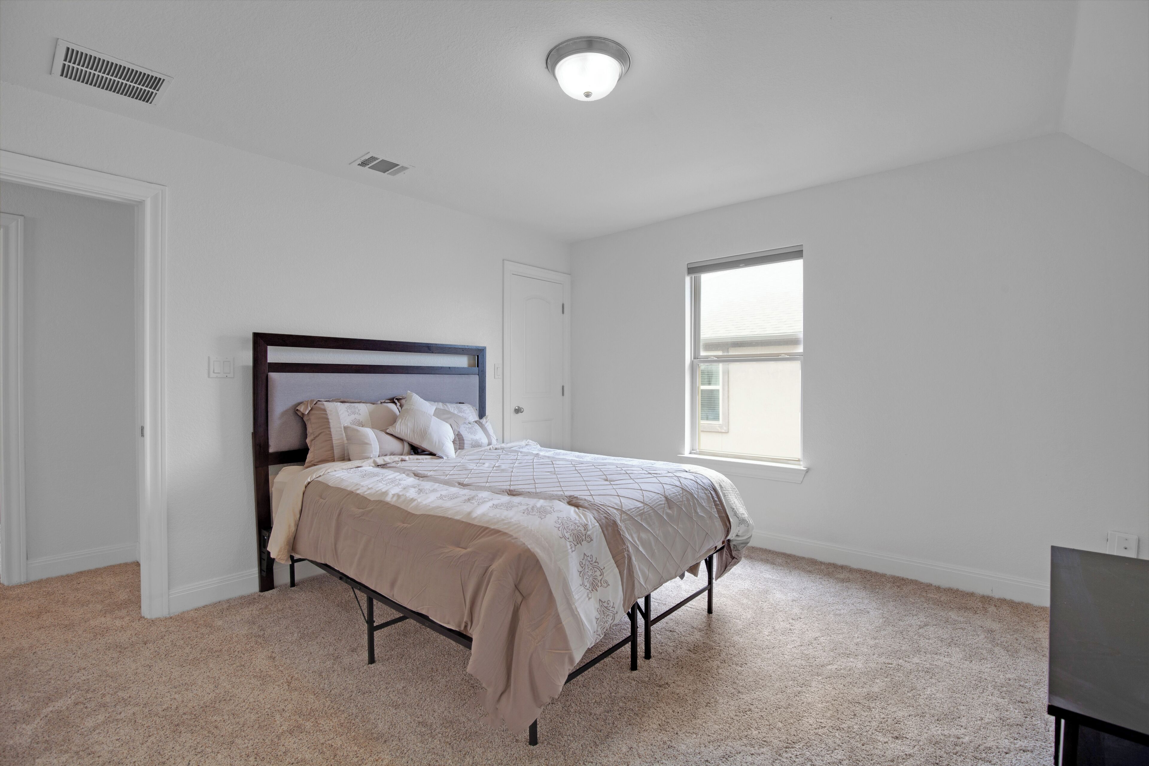 A bedroom with a bed, a window, and a door.