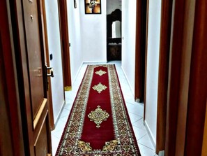 Un couloir avec un tapis rouge et des portes en bois.