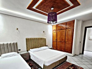 Une chambre à coucher comprenant un lit, une armoire, une table de chevet et un plafond décoratif.