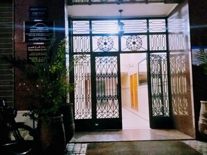 A gated entrance with decorative metalwork, a potted plant, and a sign on the wall.
