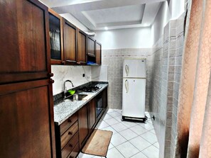 Une cuisine avec des meubles de rangement en bois, un évier, une cuisinière et un réfrigérateur blanc.