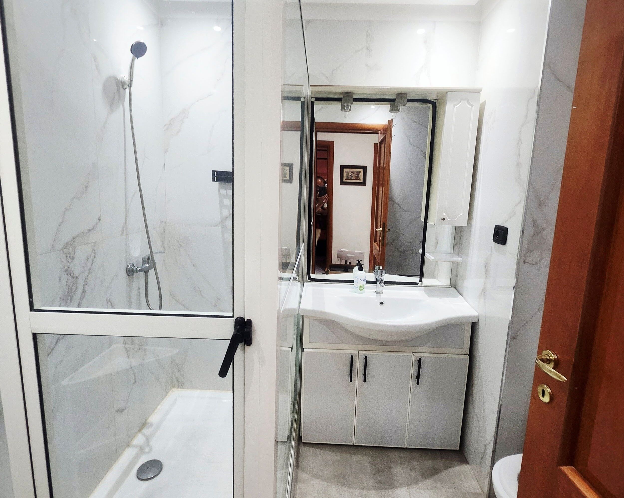 Ein Badezimmer mit Duschkabine, Waschbecken mit Spiegel und Toilette.