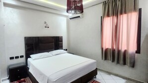 A modern bedroom with a large bed, a nightstand, a decorative ceiling, and a window with curtains. - Modern apartment Guéliz center - spacious - Parking (Marrakech)