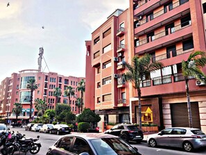 A multi-story building with balconies, parked cars, and palm trees. - Modern apartment in the heart of Guéliz – spacious – parking (Marrakech)