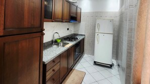 A kitchen with wooden cabinets, a sink, a stove, and a white refrigerator. - Modern apartment Guéliz center - spacious - Parking (Marrakech)