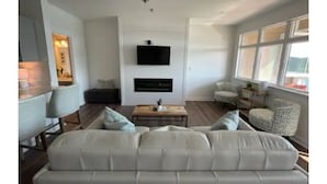 Un salon moderne avec un grand canapé, un téléviseur à écran plat fixé au mur et une cheminée.