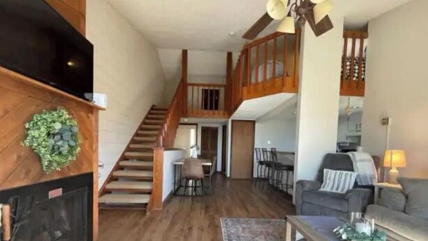 Uma sala de estar ampla com escada de madeira, lareira, área de jantar e varanda.