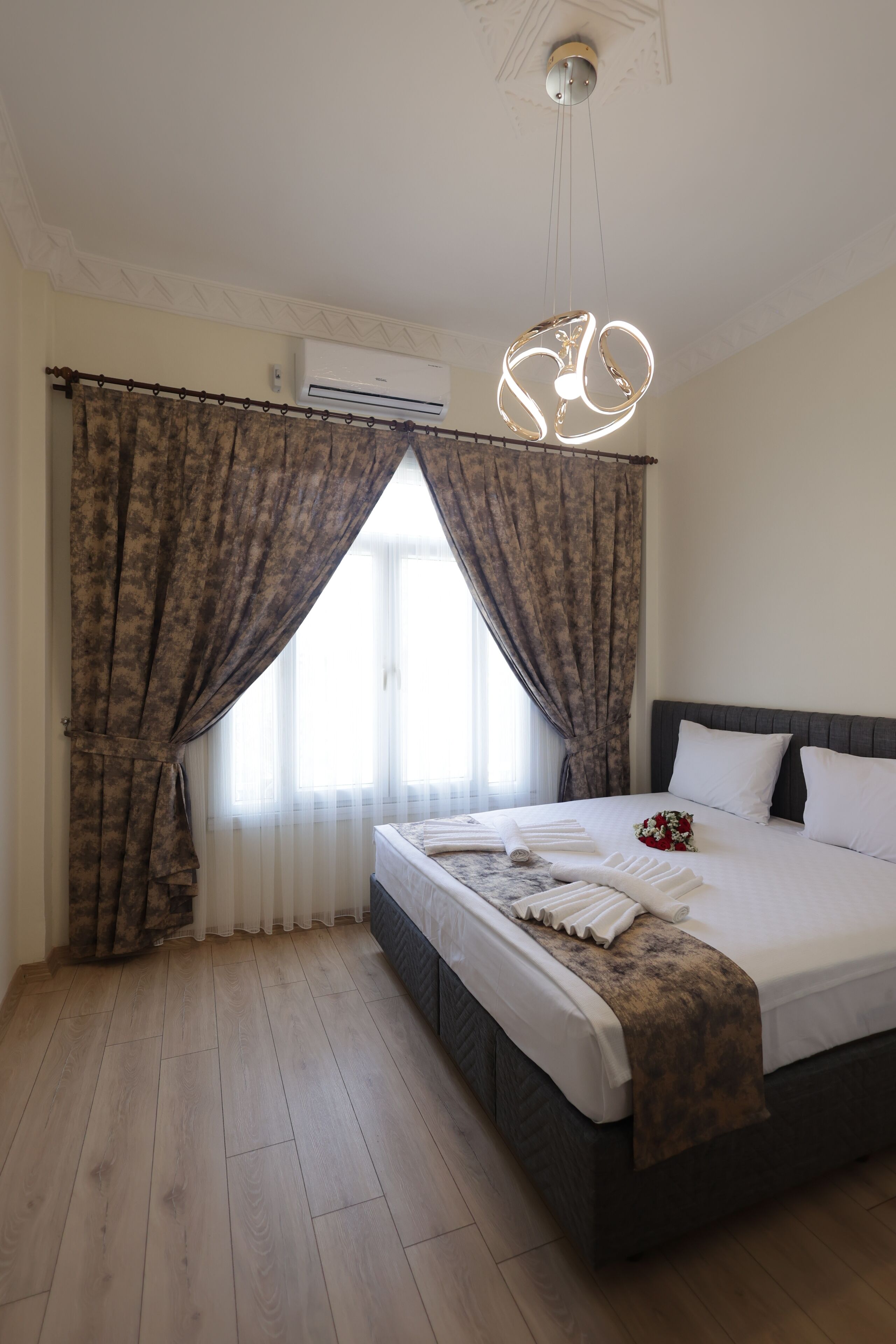 Ein Schlafzimmer mit Bett, Vorhängen, einer Klimaanlage und einer Pendelleuchte.
