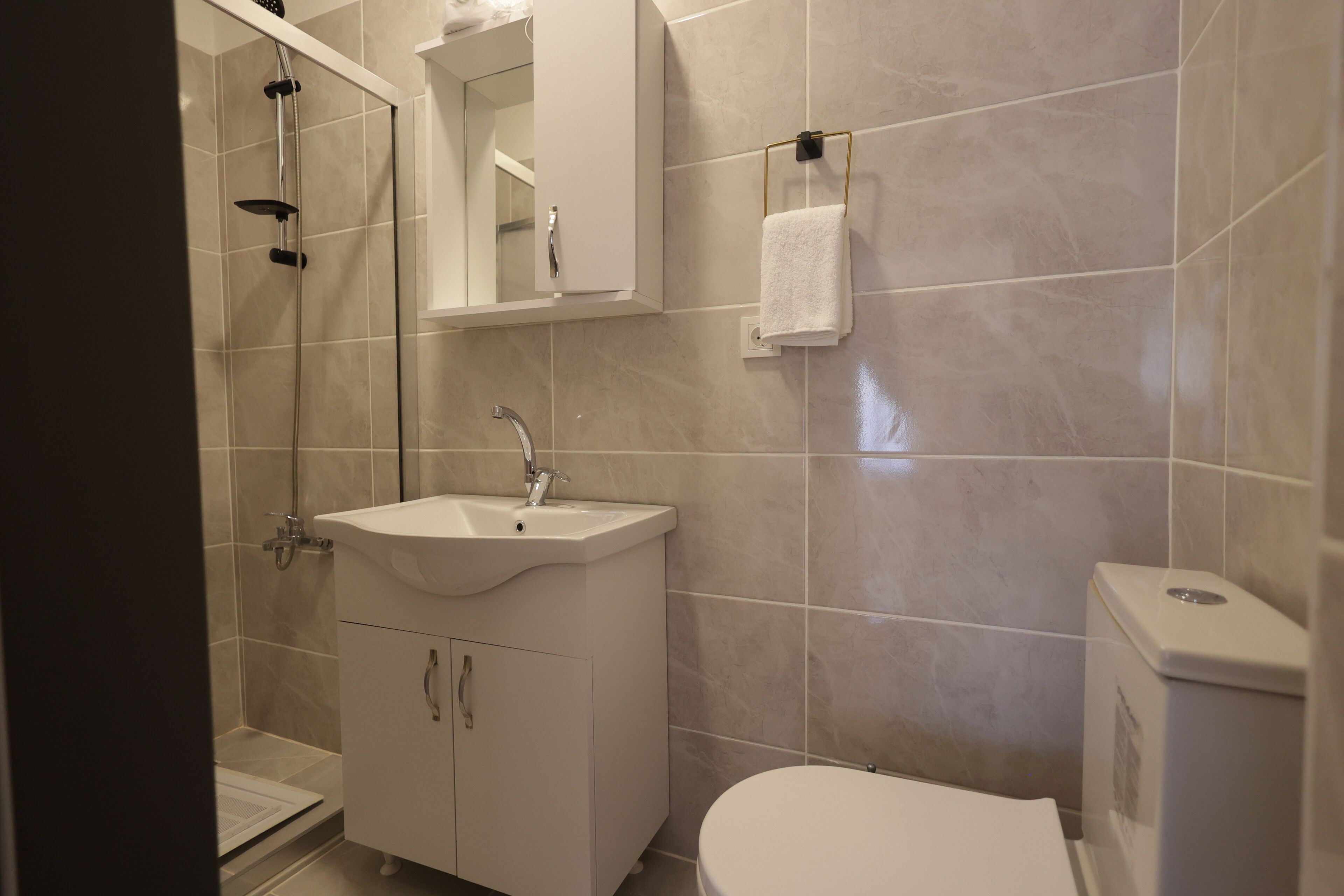 A modern bathroom with a white sink, mirror, and toilet.