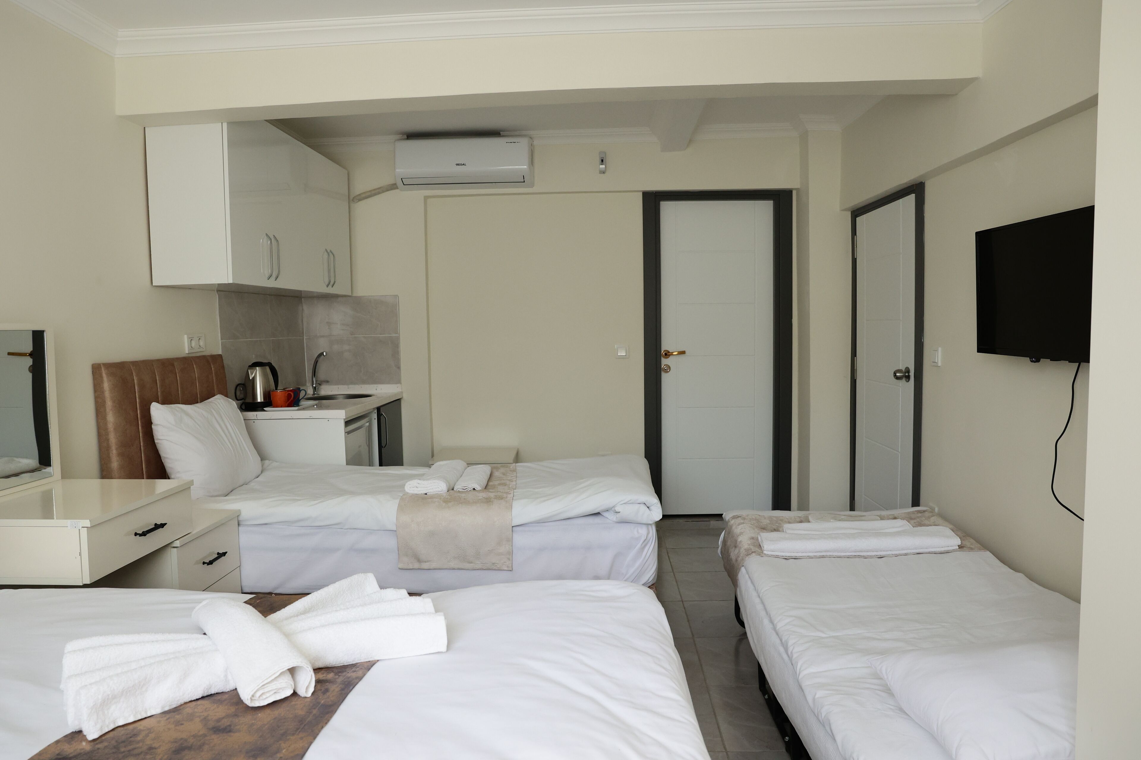 Une chambre d’hôtel avec deux lits, un bureau avec une machine à café, une télévision et une armoire.