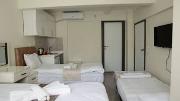 Habitación de hotel con dos camas, un escritorio con cafetera, televisor y armario.