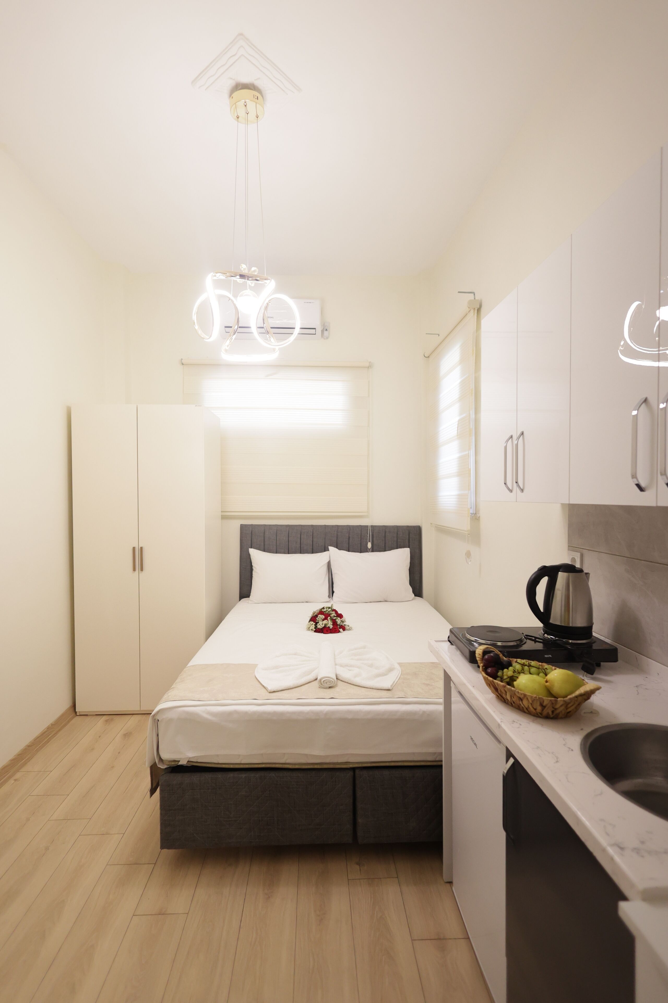 Une chambre à coucher de taille réduite, comprenant un lit, une table de chevet et un petit coin cuisine.
