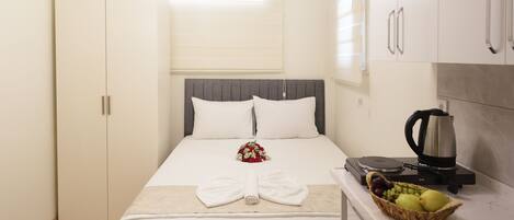 Une chambre à coucher de taille réduite, comprenant un lit, une table de chevet et un petit coin cuisine.