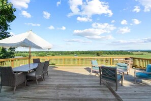A wooden deck with outdoor furniture, including a table and chairs, and a large umbrella. - Mountain View Cottage @ 66-acre Horse Farm (Berryville)