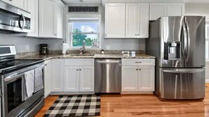 Una cocina moderna con armarios blancos, electrodomésticos de acero inoxidable y un letrero de estilo rústico.