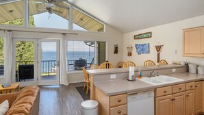 Eine moderne Küche mit einer großen Kochinsel, Holzschränken und Blick auf das Meer.