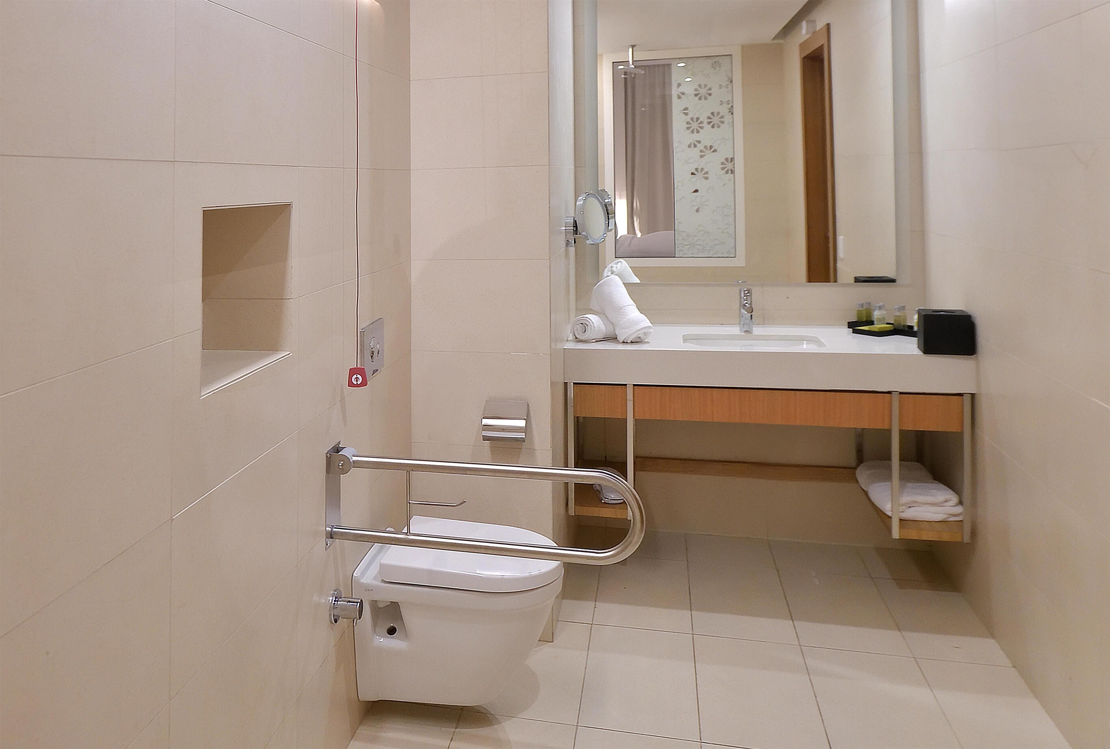A bathroom with a toilet, sink, mirror, and a shower area.