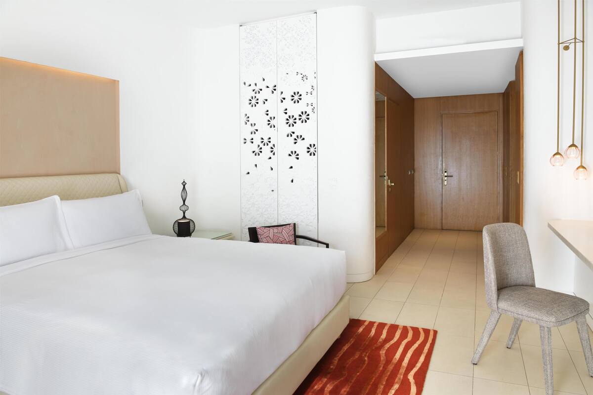 Een moderne hotelkamer met een groot bed, een bureau, een stoel en een garderobe.